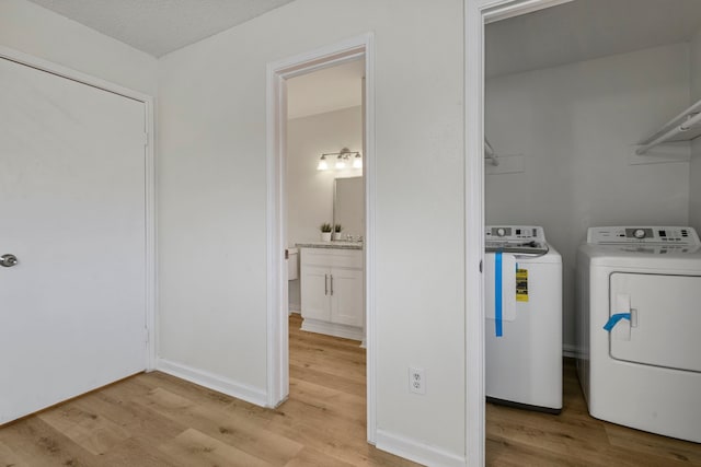 laundry room featuring a textured ceiling, washing machine and dryer, and light hardwood / wood-style flooring