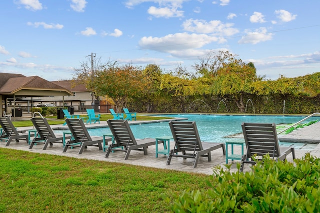 view of swimming pool with a lawn and pool water feature