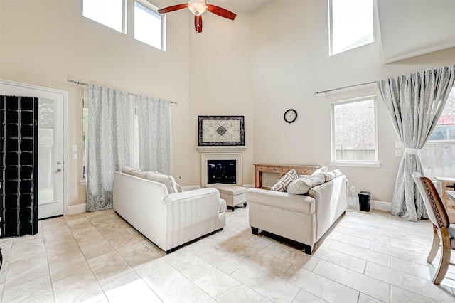 tiled living room with ceiling fan, a wealth of natural light, and a high ceiling