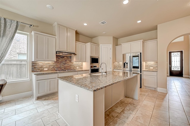 kitchen with white cabinetry, backsplash, a kitchen island with sink, and appliances with stainless steel finishes