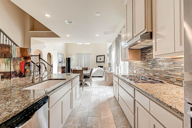 kitchen with appliances with stainless steel finishes, tasteful backsplash, light stone counters, and sink