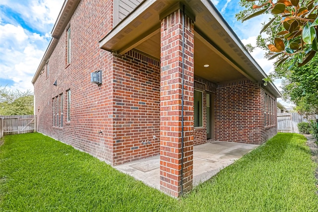 view of side of home with a patio area and a lawn