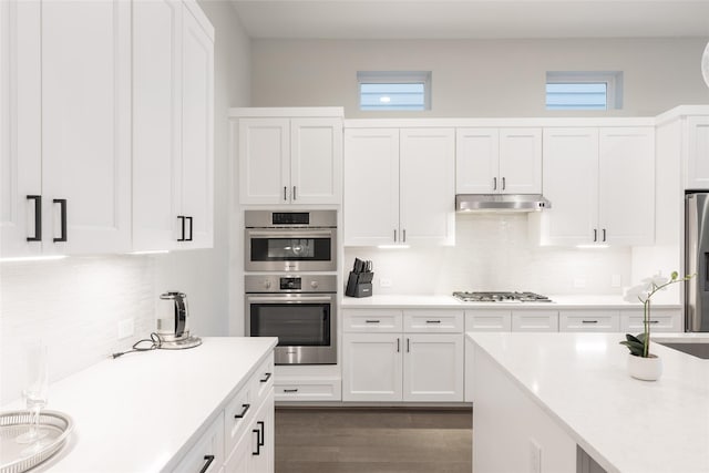 kitchen featuring appliances with stainless steel finishes, dark wood-type flooring, sink, white cabinetry, and plenty of natural light