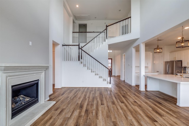 unfurnished living room featuring sink, light hardwood / wood-style floors, and a high ceiling