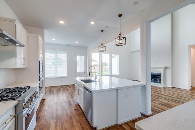 kitchen featuring white cabinetry, sink, dark wood-type flooring, hanging light fixtures, and an island with sink