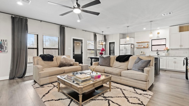 living room with ceiling fan, sink, and light wood-type flooring