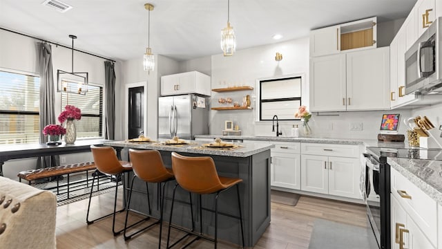 kitchen with white cabinets, light hardwood / wood-style floors, light stone counters, and appliances with stainless steel finishes