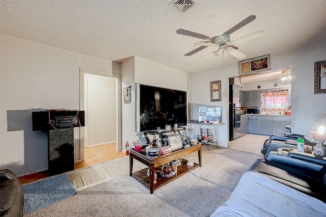 carpeted living room featuring a textured ceiling and ceiling fan