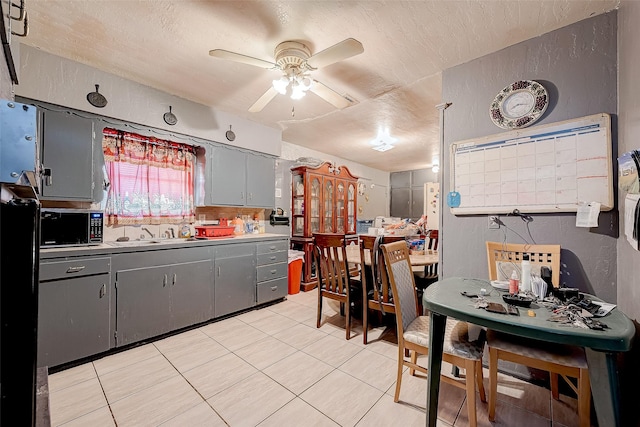 kitchen featuring gray cabinetry, ceiling fan, sink, a textured ceiling, and light tile patterned floors