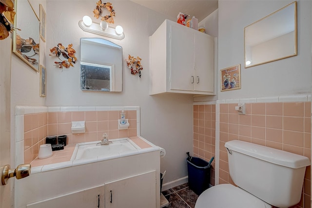 bathroom featuring tile patterned floors, vanity, toilet, and tile walls