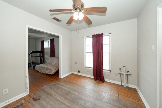 empty room with hardwood / wood-style floors, plenty of natural light, and ceiling fan