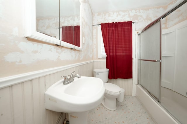 full bathroom featuring shower / bath combination with glass door, sink, tile patterned flooring, and toilet