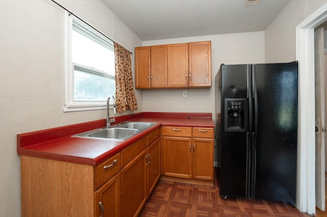 kitchen featuring dark parquet floors, black fridge, and sink