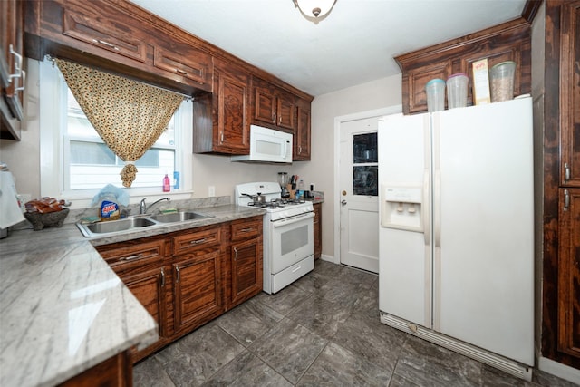 kitchen with light stone countertops, white appliances, and sink