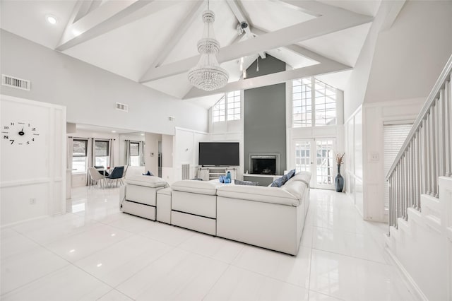 living area with stairway, light tile patterned floors, visible vents, and high vaulted ceiling