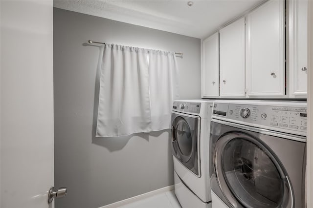 clothes washing area with washer and dryer, light tile patterned floors, and cabinets