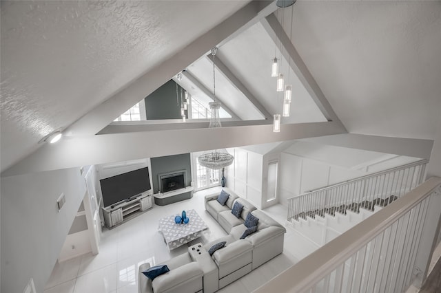 living room with light tile patterned floors, a textured ceiling, an inviting chandelier, and vaulted ceiling