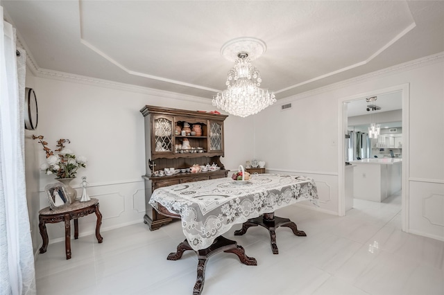 dining space with a wainscoted wall, crown molding, visible vents, a decorative wall, and an inviting chandelier