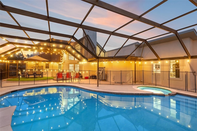 pool at dusk with a lanai, an in ground hot tub, and a patio