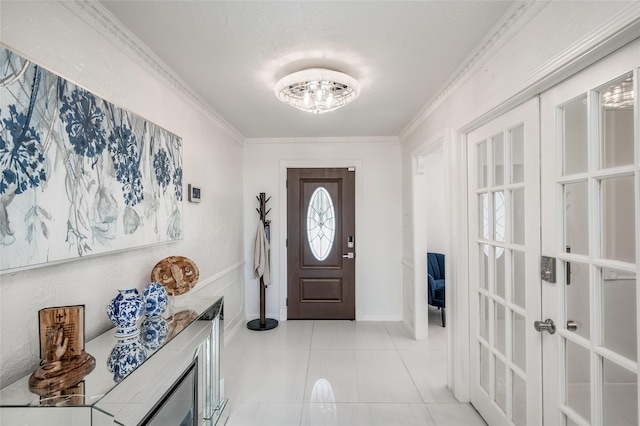 foyer entrance with light tile patterned floors, ornamental molding, and french doors