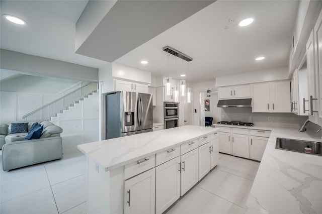 kitchen featuring stainless steel appliances, white cabinetry, a sink, a kitchen island, and under cabinet range hood