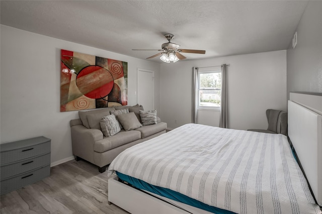 bedroom featuring ceiling fan, light hardwood / wood-style floors, and a textured ceiling