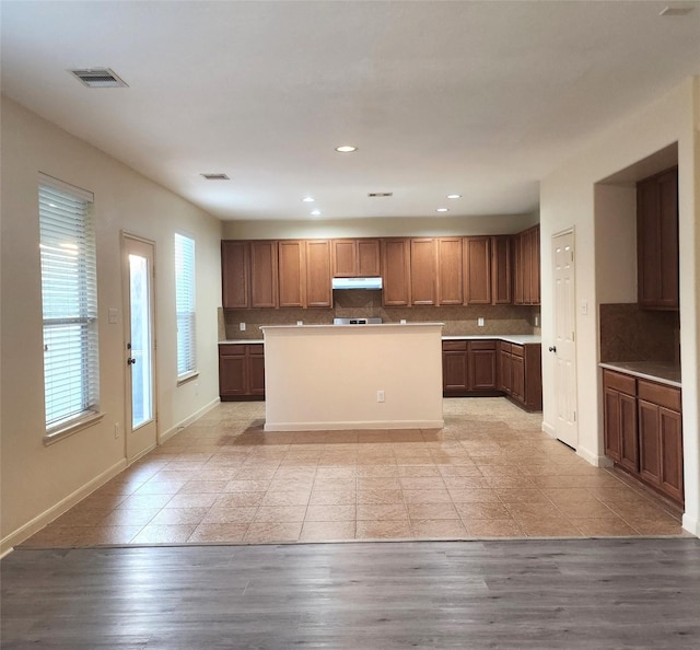 kitchen with decorative backsplash, a center island, and light hardwood / wood-style flooring