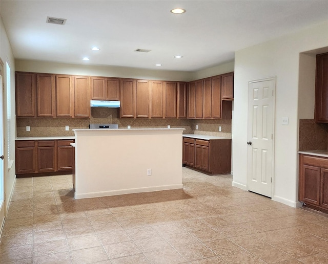 kitchen featuring decorative backsplash, a kitchen island, and light tile patterned floors