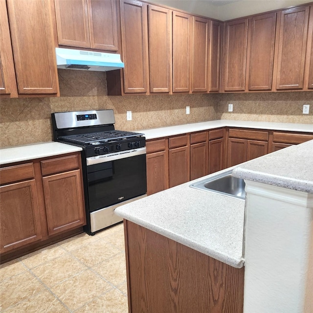 kitchen with tasteful backsplash, stainless steel gas range oven, and light tile patterned floors