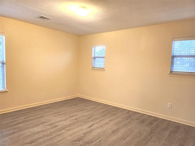 unfurnished room featuring dark hardwood / wood-style flooring and a textured ceiling