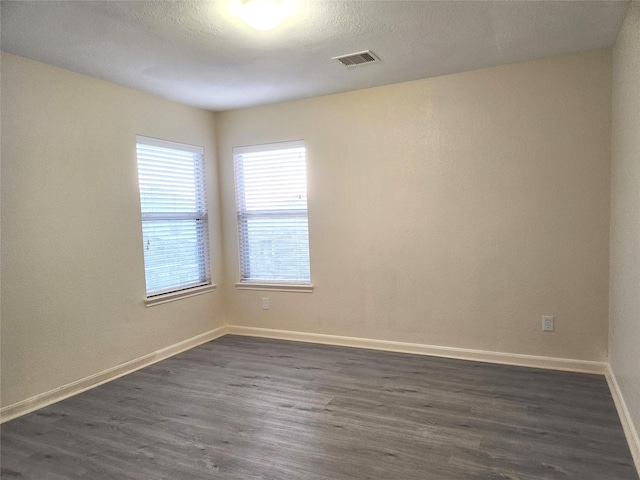 spare room with a textured ceiling and dark hardwood / wood-style floors