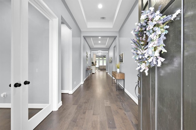 hallway featuring a raised ceiling and dark wood-type flooring