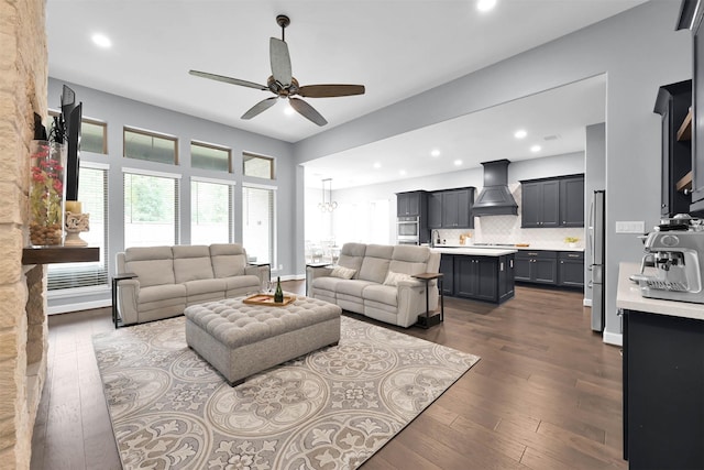 living room featuring dark hardwood / wood-style flooring, ceiling fan with notable chandelier, and sink