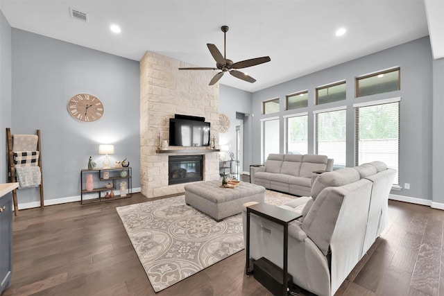 living room with ceiling fan, dark hardwood / wood-style flooring, and a stone fireplace