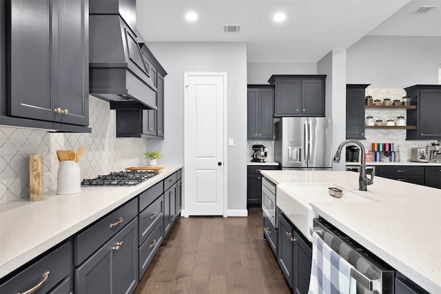 kitchen with appliances with stainless steel finishes, dark hardwood / wood-style flooring, decorative backsplash, sink, and custom range hood