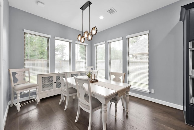 dining space featuring dark wood-type flooring, plenty of natural light, and an inviting chandelier