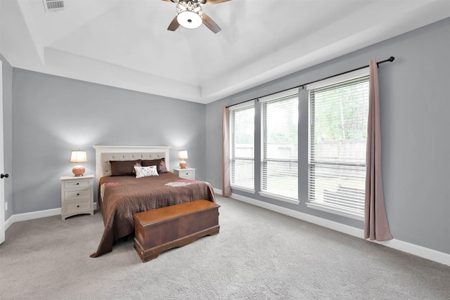 carpeted bedroom featuring ceiling fan and a raised ceiling