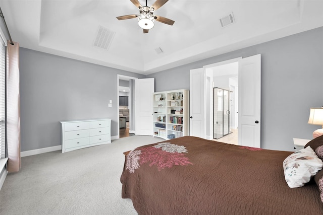 bedroom with ceiling fan, a tray ceiling, and light carpet