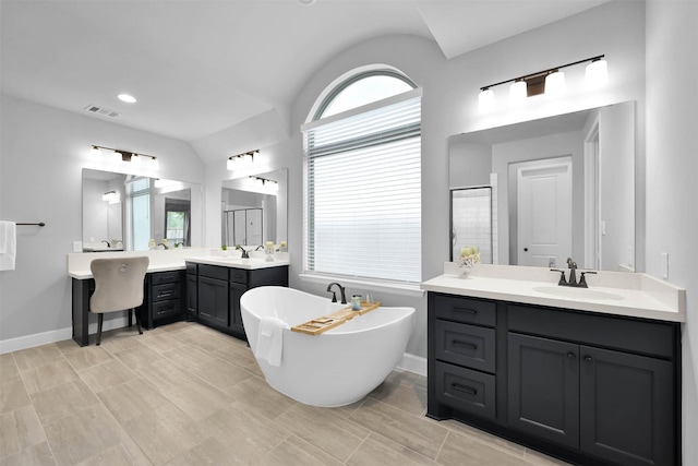 bathroom featuring a wealth of natural light, a bathtub, vanity, and vaulted ceiling