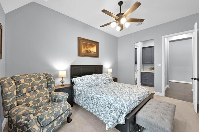 bedroom featuring light carpet, ceiling fan, and ensuite bath