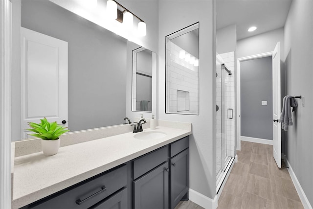 bathroom featuring a shower with shower door and vanity