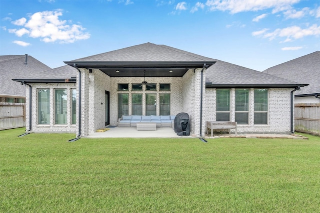 rear view of property featuring ceiling fan, a patio area, an outdoor living space, and a lawn