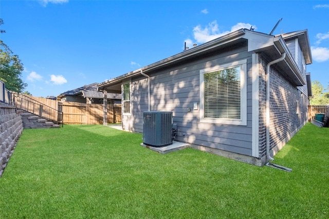 back of property featuring central AC and a lawn