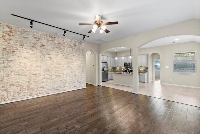 unfurnished living room with light wood-type flooring, track lighting, and ceiling fan