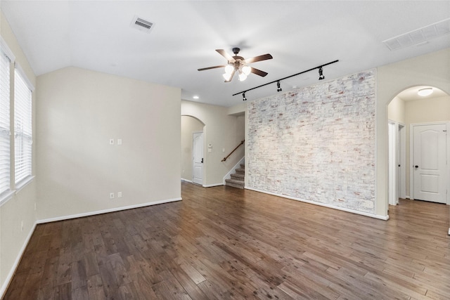 empty room featuring a wealth of natural light, track lighting, dark hardwood / wood-style floors, and ceiling fan