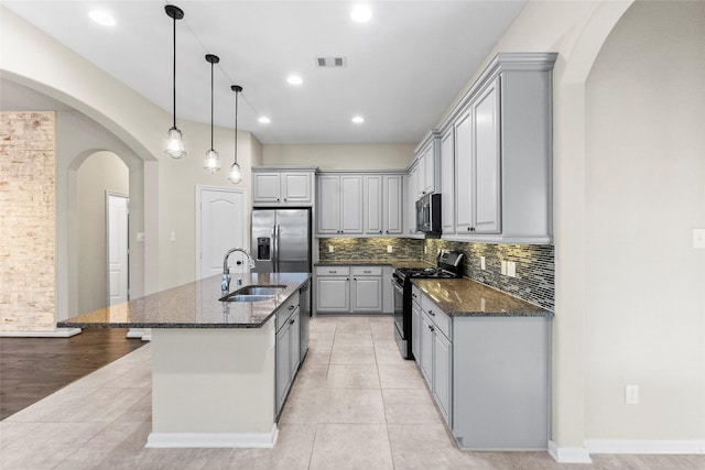 kitchen featuring stainless steel appliances, a kitchen island with sink, gray cabinetry, and sink