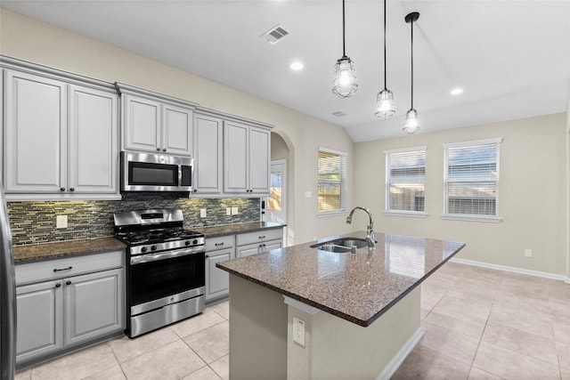 kitchen with backsplash, a center island with sink, sink, gray cabinets, and appliances with stainless steel finishes