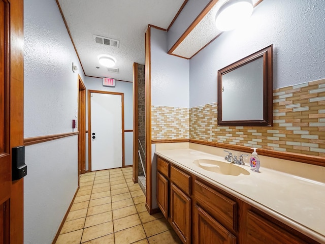 bathroom featuring vanity, a textured ceiling, tasteful backsplash, and tile patterned floors