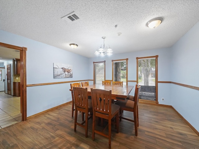 dining area featuring a textured ceiling, dark wood-type flooring, and a chandelier