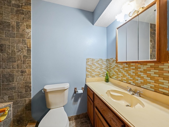 bathroom with decorative backsplash, vanity, and toilet